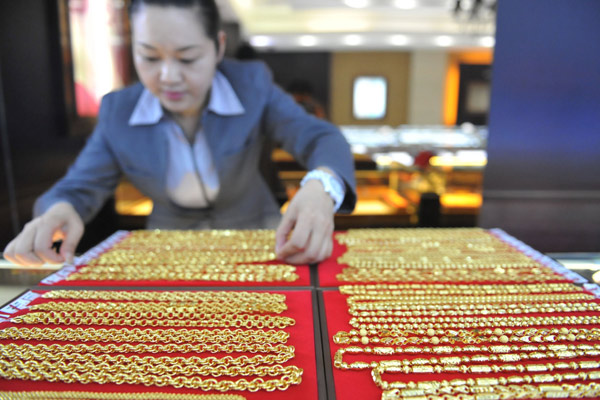 A saleswoman sorts gold products at a shop in Lin'an, Zhejiang province. Chinese consumers bought 182.7 metric tons of jewelry, gold bars and coins for investment in the third quarter, a 37 percent year-on-year decline. [Hu Jianhuan / China Daily]   