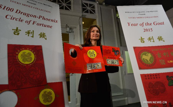 US Treasurer Rosie Rios displays the  Year of the Goat 2015 and $100 Dragon-Phoenix Circle of Fortune lucky money notes during a press conference in Washington D.C., capital of the United States, Dec 2, 2014.  (Xinhua/Bao Dandan)