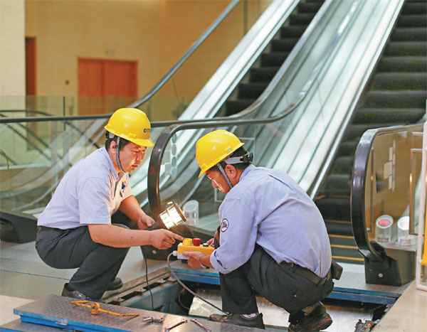 Two of Otis' Chinese technicians doing repairs in Tianjin. The maintenance and service business in China is expected to give a lift to the industry. Long Wei / For China Daily  