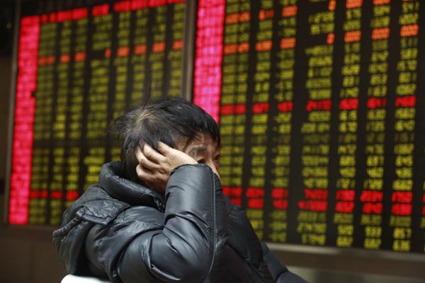 An investor checks share prices at a brokerage in Beijing. Financial sector shares crashed on Jan 19, 2015 with many brokerages, banks and insurers seeing major declines. [Photo/China Daily] 