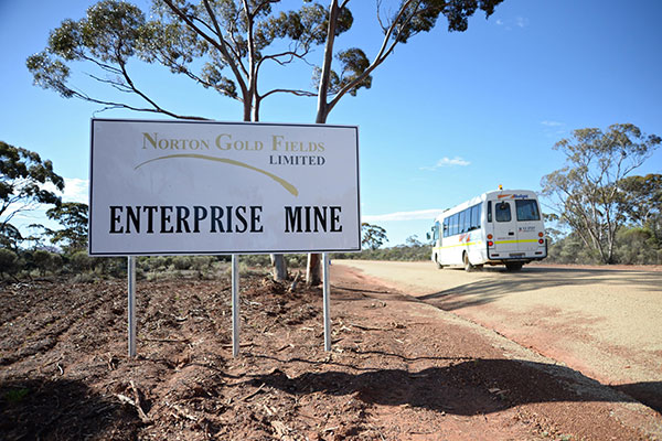 A bus drives past a sign displayed at the entrance to the Norton Gold Fields Ltd, which is northwest of Kalgoorlie, Australia. Norton, the Australian miner, is controlled by China's Zijin Mining Group Co. (Photo/China Daily)