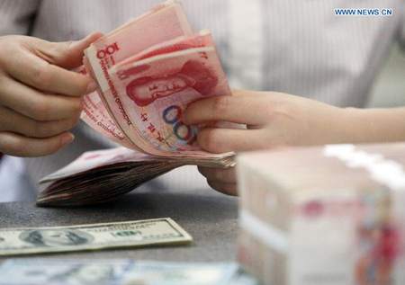 A worker counts Chinese currency Renminbi (RMB) at a bank in Linyi, east China's Shandong Province, Aug. 11, 2015. (Photo: Xinhua/Zhang Chunlei)