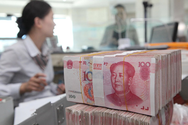 An employee counts renminbi (yuan) banknotes at a bank in Lianyungang city, East China's Jiangsu province, June 4, 2014. (Photo provided to China Daily)