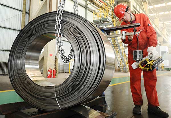 A worker at a steel plant in Dalian, Liaoning province, weighs alloy strips.(Liu Debin/For China Daily)