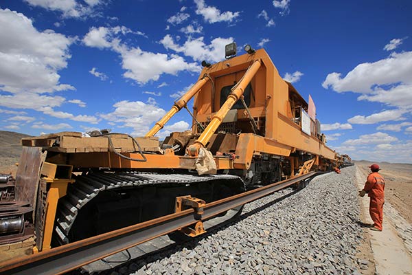 A worker monitors a track laying machine in a construction site of a railway project in Hami, Xinjiang Uygur autonomous region.(Provided to China Daily)