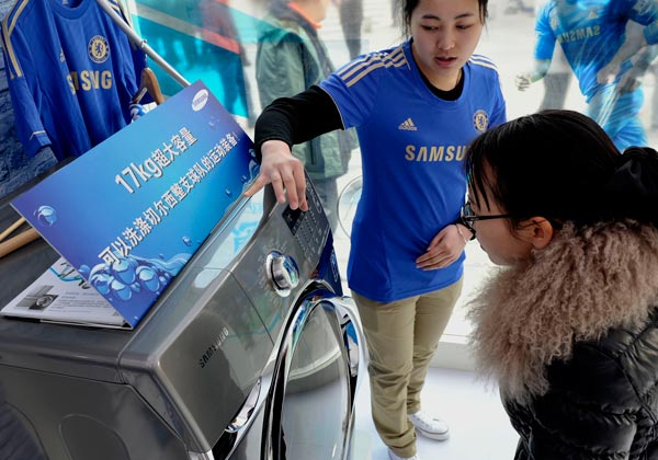 A saleswoman demonstrates the features of a Samsung washing machine at a store in Nanjing, Jiangsu province.(Photo/China Daily)