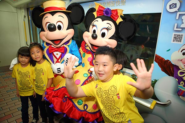 Children pose for pictures with Mickey and Minnie Mouse at a subway station in Shenzhen as part of a promotion by Hong Kong Disneyland Resort on Nov 15, 2015. Winners could get tickets to the Hong Kong park.(Provided to China Daily)