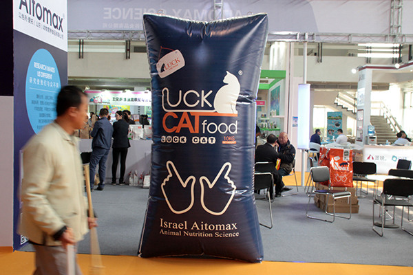 A man passes by a giant cat food advertisement at a pet food and necessities fair in Beijing. (Photo/China Daily)