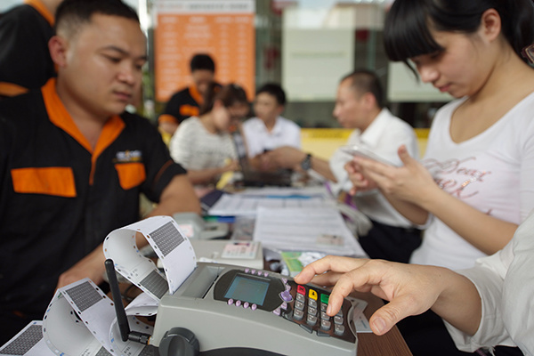 A bank in Qionghai, Hainan province, issues a bank card to a local resident. The China Banking Regulatory Commission has urged all commercial banks to issue bank cards using real names of the holders in a move to fight new frauds.Photo/China Daily