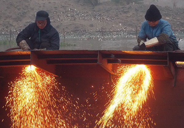 A worker dismantles a 100-ton cargo vessel at a wharf in Shaoxing, Zhejiang province. (Rui Chang/For China Daily)