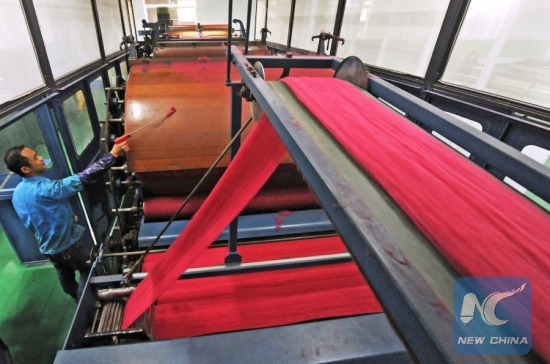 A staff member dusts a machine at a textile company in the Nanxun District of Huzhou City, east China's Zhejiang Province, Dec. 25, 2014. (Xinhua/Tan Jin) 