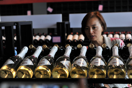 A woman examines imported wines at a duty-free shop in Qingdao, Shandong province. (Photo/China Daily)