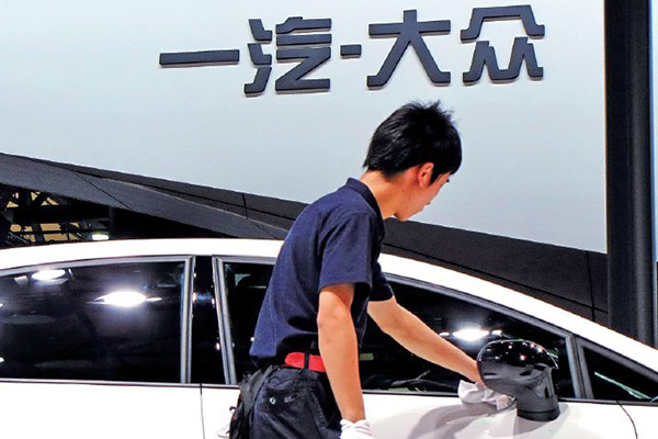 A worker cleans a new car at FAW-Volkswagen's booth at an auto show in Shanghai. International carmakers which want to localize their products are required to establish joint ventures, in which their stake cannot exceed 50 percent. (Photo/China Daily)