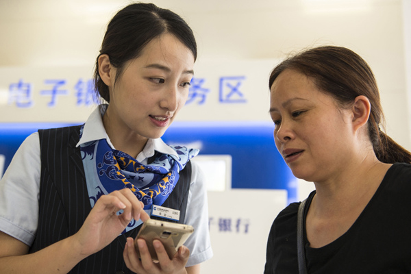 An employee of China Construction Bank helps a client at a branch in Haian, Jiangsu province. (Photo by Xu Jinbai/For China Daily)