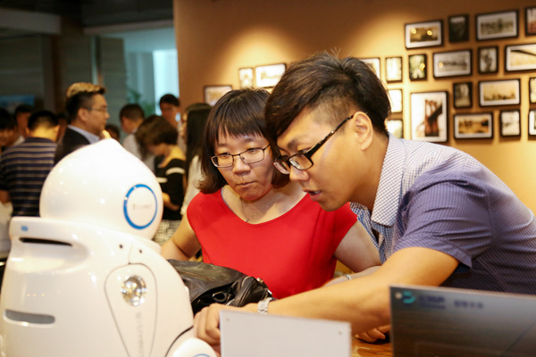 Visitors interact with a robot equipped with Unisound's intelligent voice recognition technology at a conference in Beijing in July 2016. (Photo provided to China Daily)