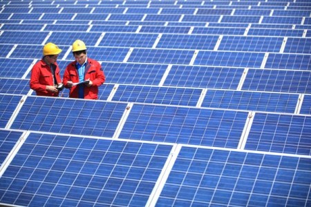 Technicians check solar panels at a textile company in Jimo, Shandong province. (Photo/China Daily)