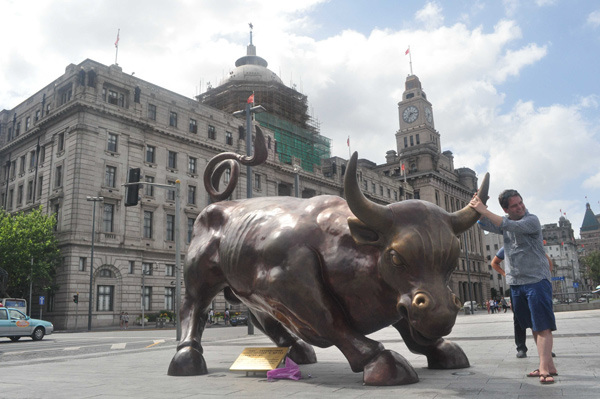 A tourist poses in front of the bull statue at the Bund in Shanghai. The city has progressed in rankings of global financial centers. (Photo by Yan Daming/For China Daily)