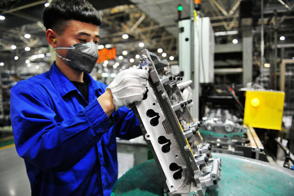 A worker checks components at an engine plant of SAIC-GM-Wuling Automobile Co in Qingdao, Shandong province. (Photo by Yu Fangping/China Daily)