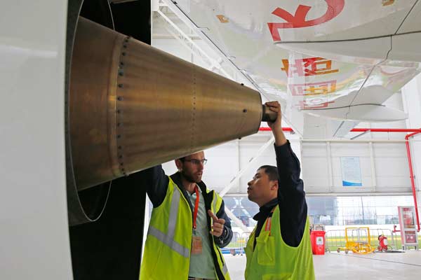 Workers inspect the engine of the C919 after its test taxing two days before its maiden flight at Shanghai Pudong International Airport on Friday. (Photo/China Daily)