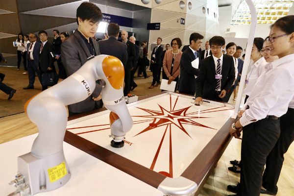 An industrial robot interacts with a participant of the Dalian Summer Davos Annual Meeting at the Dalian International Conference Center in Dalian, Northeast China's Liaoning province, June 27, 2017. (Photo by Zhu Xingxin/chinadaily.com.cn)