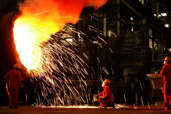 Workers clean a molten steel holder at a steel plant in Dalian, Liaoning province. (Photo by Liu Debin/For China Daily)