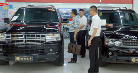 A customer (left) checks a second-hand car at an automobile trading company in Suzhou, Jiangsu province. Photo by Wang Jiankang/For China Daily)