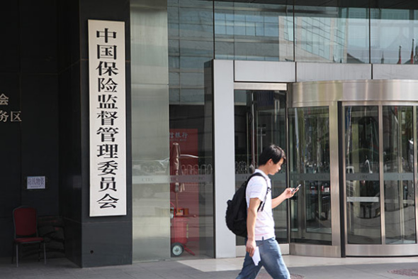 A visitor checks his cellphone at the gate of the China Insurance Regulatory Commission. (Photo: Liu Yuanrui/China Daily)