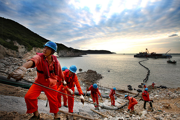 Workers from State Grid Corp of China lay an underwater cable in Zhoushan, Zhejiang province. (Yao Feng/for China Daily)