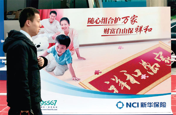 A man passes by the billboard of New China Life Insurance Co at an insurance fair in Beijing. (Photo by A Qing/For China Daily)