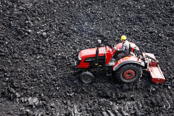 A man operates a tractor to crush coal, one of the fuels used by the thermal power industry, in Huaibei, Anhui province. (Photo by WU HE/CHINA DAILY)