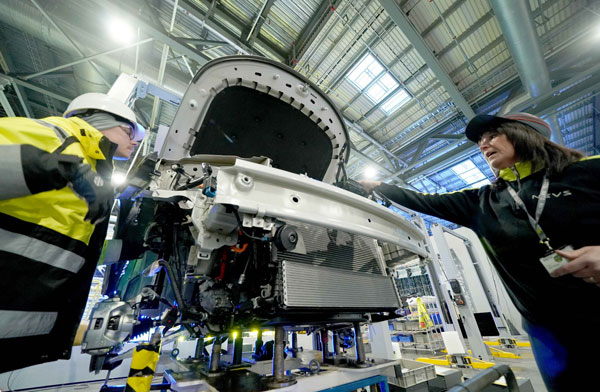 Technicians adjust manufacturing equipment at a new energy vehicle production line in Tianjin last month. (Photo/Xinhua)