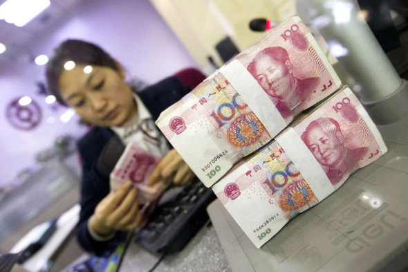 A cashier at a bank in Taiyuan, Shanxi province, counts renminbi notes. (Photo by Zhang Yun/China News Service)