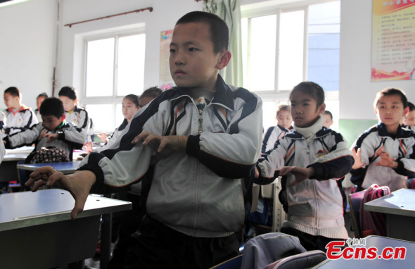 Students from Guangminglu Primary School in Shijiazhuang city of Hebei province practice some martial arts movements believed to be able to strengthen the body's resistance against smog, on Dec 11, 2013. School officials said certain movements could help lungs discharge harmful substances.