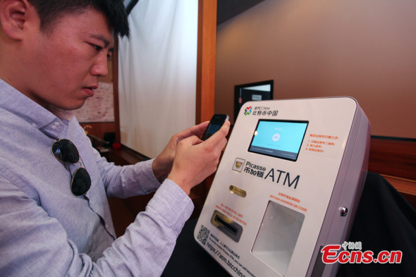 A man takes photos of a Bitcoin ATM at a caf in Zhangjiang Hi-Tech Park of Shanghai municipality on April 15, 2014. The machine is China's first Bitcoin ATM. [Photo: China News Service / Zhang Hengwei]