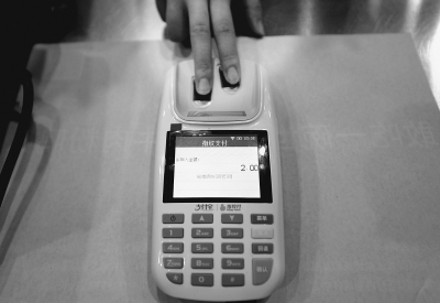 A customer pays for a bottle of Coke by scanning fingerprints at Funiutang restaurant on Tuesday. (Photo: Beijing Daily)