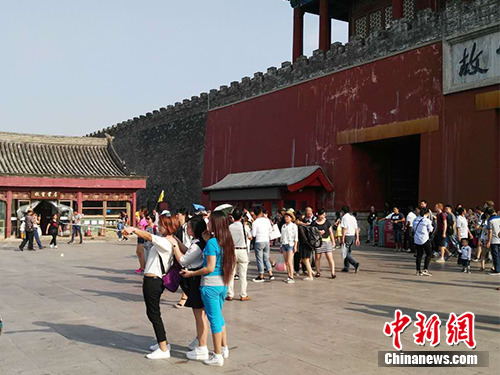 Visitors use a selfie-stick to take photos outside of the Palace Museum in Beijing. (File photo/Chinanews.com)