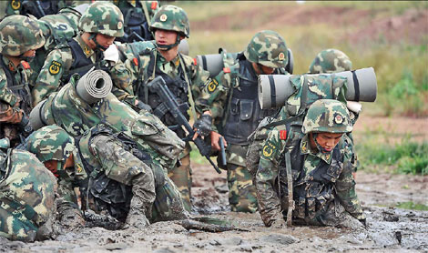 Contestants crawl through mud during the training session for Yunnan Satellite TV's reality show, Soldiers' Sortie. Photos Provided to China Daily