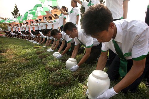 A mass funeral is held in Tianjin in 2010. People put the ashes of their loved ones in dissolvable urns and bury them in the soil.