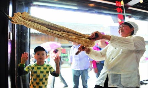 A lady makes candied ginger, which is believed to lessen inner heat.