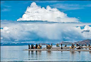 People stand on the bank of the Nam Co Lake, the highest saltwater lake in the world, in Tibet on Aug 8. Purbutashi / Xinhua