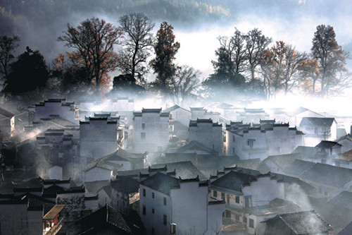 Village residences are shrouded in the early morning mist, in Wuyuan. Shi Guangde / For China Daily