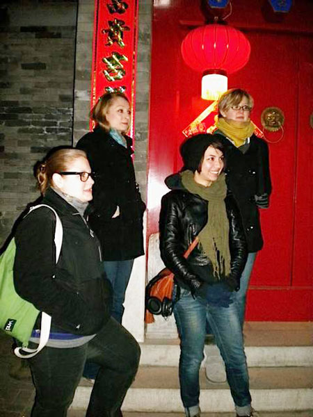 A group of tourists explore an old hutong in the neighborhood of Houhai, where tour guides share ghost stories with the visitors. Provided to China Daily