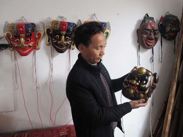 Cheng Hanping shows one of the antique masks, regarded as sacred artifacts in Nuo Opera. Zhang Zixuan / China Daily  