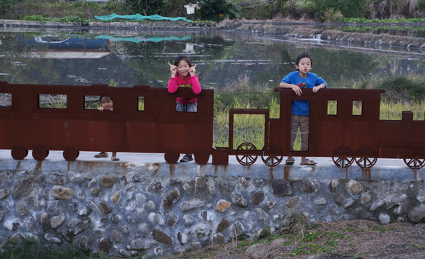 Three children pose with the train model at Tian Song Bei Station in Yilan. [Photo by Liu Hui / for China Daily]  