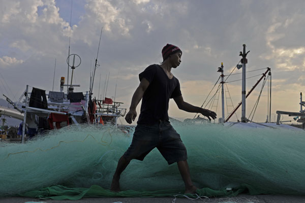 A fisherman prepares the net for a fishing trip at a port in Keelung. [Photo by Chen Jie / for China Daily]  