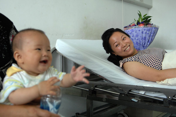 Rescuer Wu Juping smiles at her own son after she has saved a 2-year-old girl. [Photo/Xinhua]