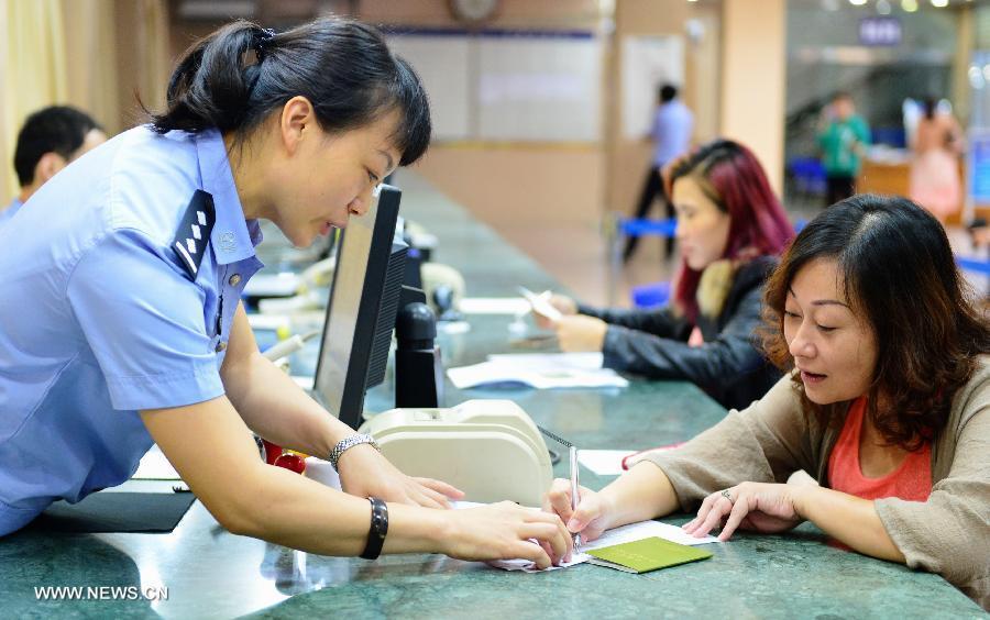 A woman from Taiwan (R front) fills in an application form for a renewed Taibaozheng, a passport-like document that carries the entry permits for Taibao, or Taiwan compatriots, in Fuzhou, capital of southeast China\'s Fujian Province, Sept. 21, 2015. The electronic version of Taibaozheng, which is in the form of a card instead of the former paper form, is enabled on the Chinese mainland on Monday. The electronic Taibaozheng, which also serves as the certificate of identity during Taiwan residents\' stay on the mainland, will bring more convenience for Taiwanese travelling between Taiwan and the mainland. (Photo: Xinhua/Wei Peiquan)