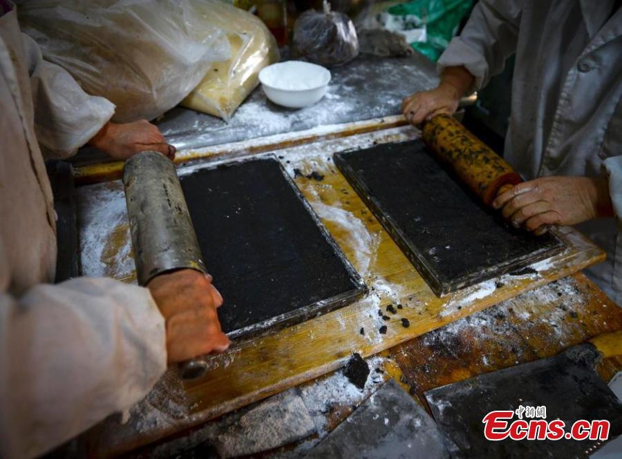 Cooks use rolling pins to prepare black sesame seed as filling for Yuanxiao. (Photo: China News Service/Liu Xin)