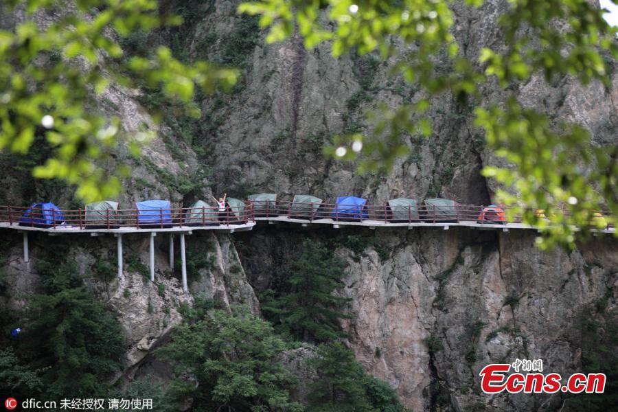 A line of tents on a suspended pathway built on the cliff, about 1,000 meters above the ground, at Laojun Mountain in Luoyang City, Central China’s Henan Province, July 16, 2016. The mountain is known for its cultural heritage relating to Taoism as it was once the retreat of Laozi, a great Chinese philosopher and the founder of Taoism. The mountain is hosting a tenting festival, which has attracted hundreds of tourists. (Photo: China News Service/Wang Zhongju)