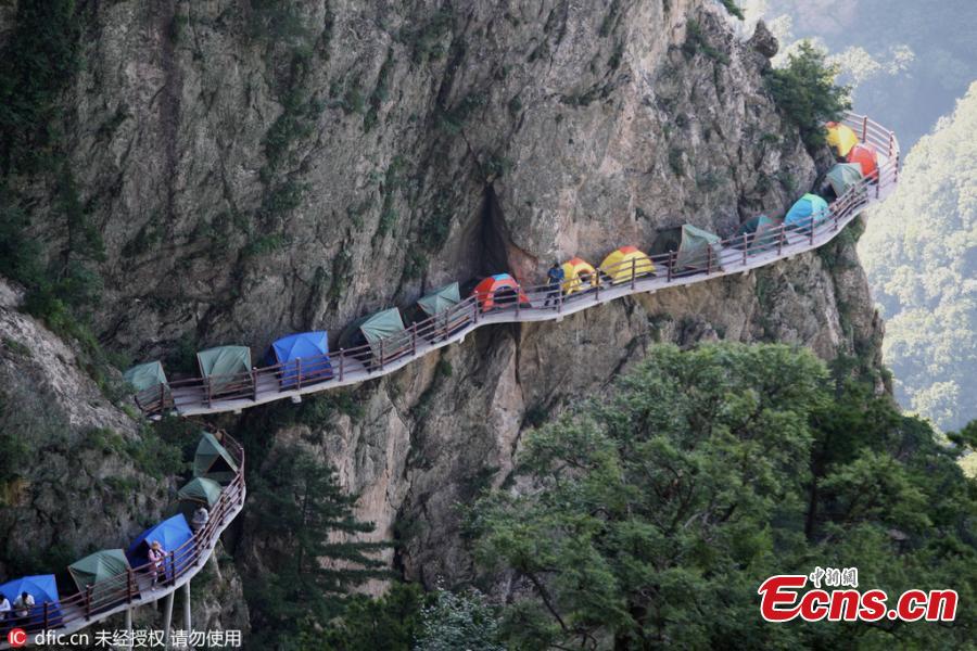 
A line of tents on a suspended pathway built on the cliff, about 1,000 meters above the ground, at Laojun Mountain in Luoyang City, Central China’s Henan Province, July 16, 2016. The mountain is known for its cultural heritage relating to Taoism as it was once the retreat of Laozi, a great Chinese philosopher and the founder of Taoism. The mountain is hosting a tenting festival, which has attracted hundreds of tourists. (Photo: China News Service/Wang Zhongju)